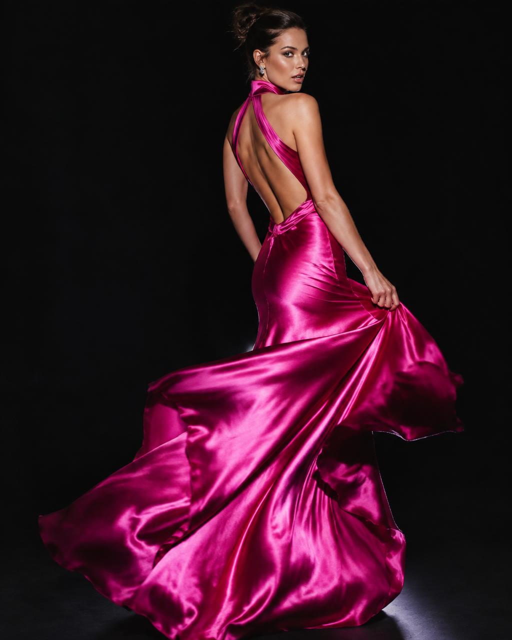 Fuchsia satin gala dress with a dramatic back cut-out under a studio spotlight